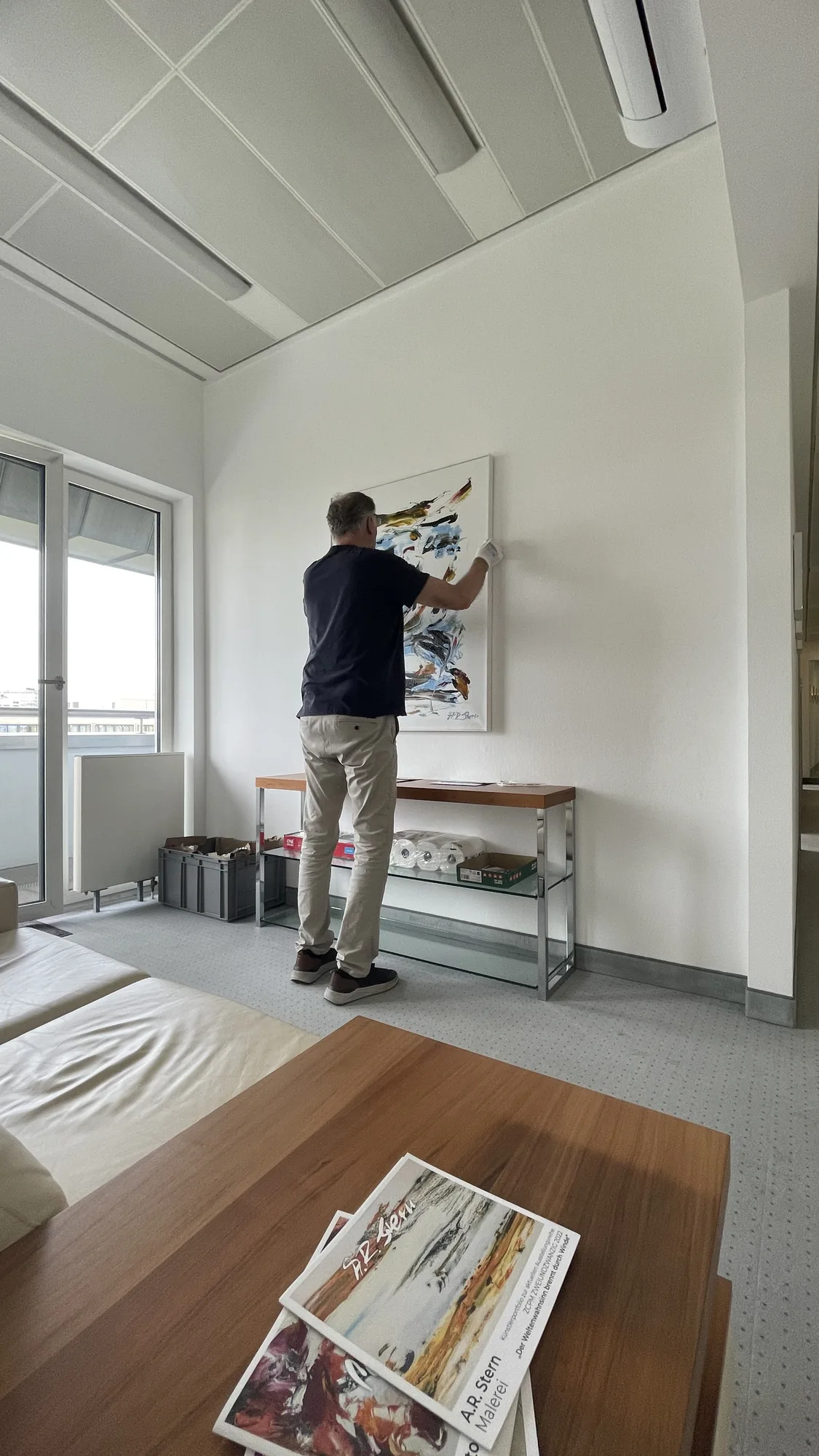 Mitarbeiter von ARTprotect hängt ein Originalgemälde in einem Nebenraum eines Berliner Büros auf
