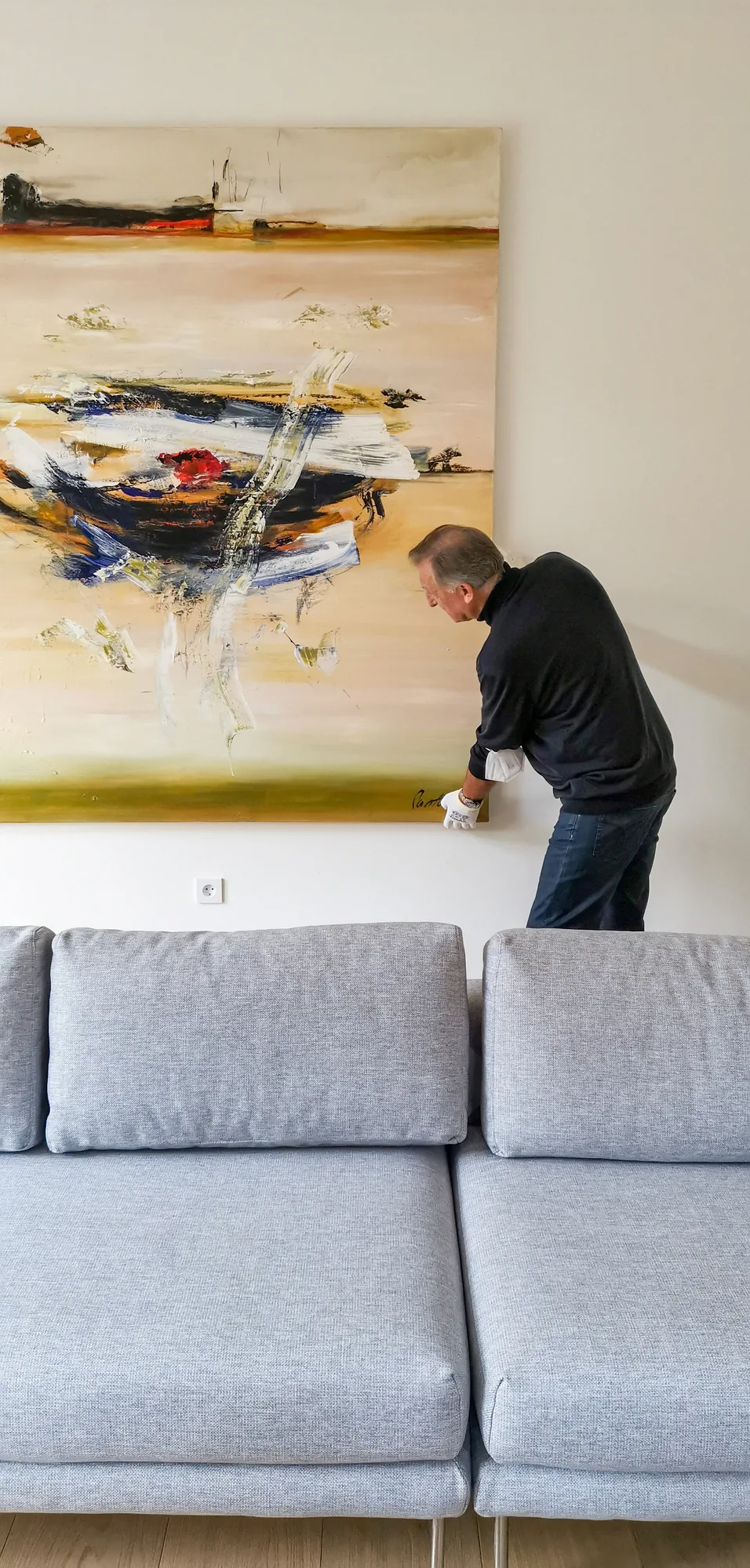 Ein Originalgemälde wird im Wohnzimmer einer Berliner Wohnung fachgerecht aufgehängt