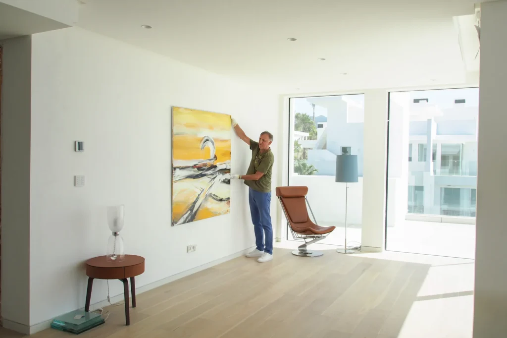 Mitarbeiter von ARTprotect hängt ein Originalgemälde im Wohnzimmer einer Berliner Wohnung auf